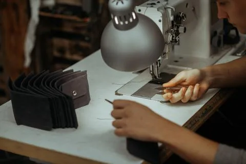 Making leather wallets on a sewing machine by a craftsman on a white table Stockfoto's