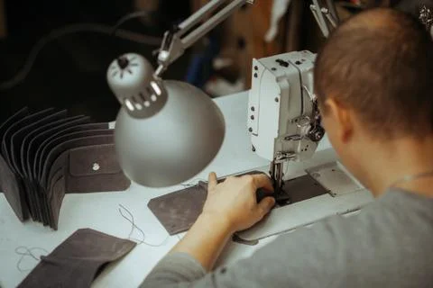Making leather wallets on a sewing machine by a craftsman on a white table Stock Photos