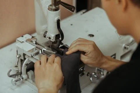 Making leather wallets on a sewing machine by a craftsman on a white table. On Stock Photos