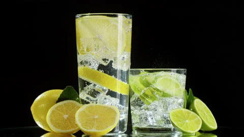 Making lime and lemon cocktail on black background. Citrus fresh drink with ice Stock Footage 169116653
