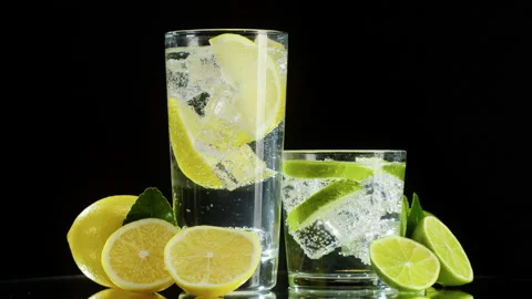 Making lime and lemon cocktail on black background. Citrus fresh drink with ice Stock Footage 169734925