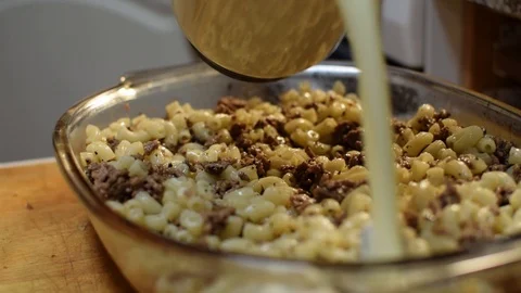 Making macaroni casserole. Pouring mixture of egg and milk into casserole Stock-Footage 94916595
