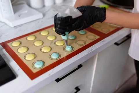 Making macaroons.The dough from the syringe is squeezed out on a baking sheet. Stock Photos