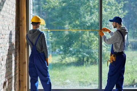 Making new home. Rear view of two young male builders wearing blue overalls Stock Photos