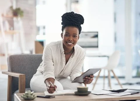 Making notes keeps me sharp. a businesswoman using her digital tablet while Stock Photos