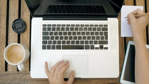 Making notes in paper notebook using a laptop pc Stock Photos