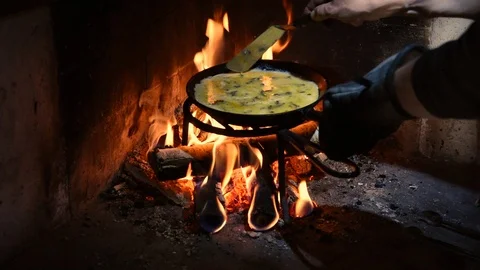 Making an omelet in a cast iron frying pan in a fireplace Stock Footage 101249052