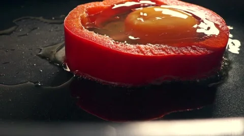 Making omelet in red sweet pepper ring. Macro frying pan shot Stockbeeldmateriaal 60605256