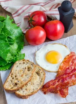 Making open face sandwich with egg, bacon, tomato and lettuce Fotos de archivo