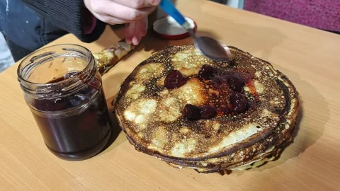 Making pancakes with cherry jam in a home kitchen in the afternoon Stock Footage 328441108