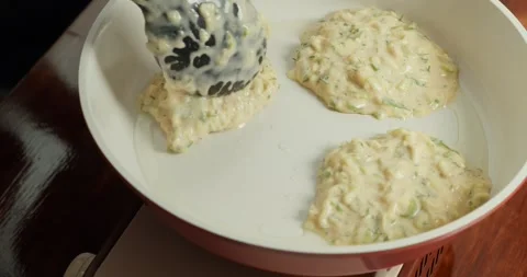 Making pancakes from grated zucchini. Close-up of zucchini fritters frying in Stock Footage 317072174