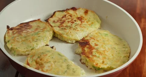 Making pancakes from grated zucchini. Close-up of zucchini fritters frying in Stock Footage 317182665