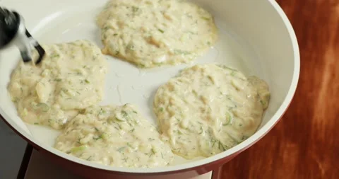 Making pancakes from grated zucchini. Close-up of zucchini fritters frying in Stock Footage 318024745