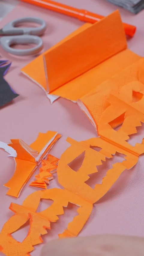 Making a paper chain of smiling pumpkin faces for autumn home decor Stock Footage 346982590