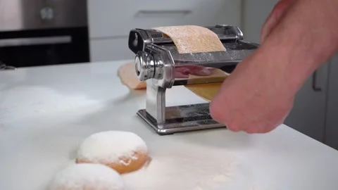 Making pasta, rolling dough on a pasta machine at home, close-up, 4K Stock Footage 132464626