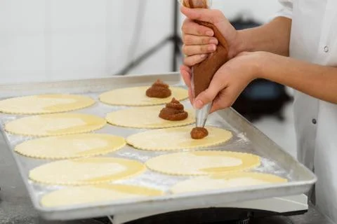 Making of pastry goods. Baker is squeezing apple jam Stock Photos