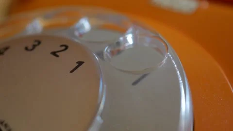 Making a phone call on an old orange rotary telephone Stock Footage 141797973