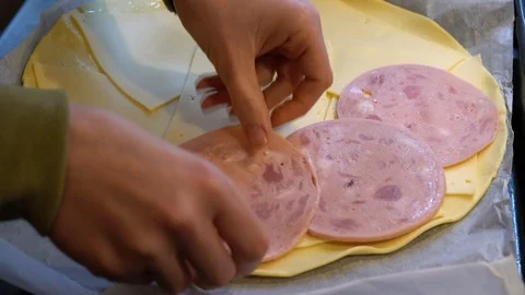 Making a pie with ham and cheese. cook puts ham on cheese while making roll. Stock Footage 123236854