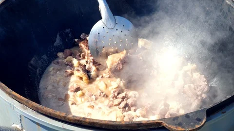 Making pilaf outdoor on open fire in cauldron. Mixes fatty meat Vidéo 113522913
