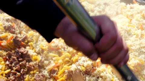 Making pilaf outdoor on open fire in cauldron. Mixes prepared pilau Vidéo 113529826