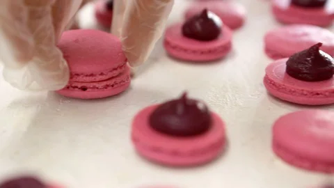 Making Pink Macaroons. Close up shot of connecting two halves of macaroons with 스톡 동영상 129784271