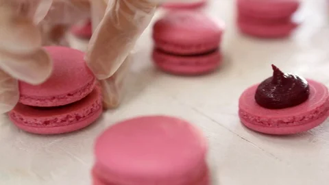 Making Pink Macaroons. Close up shot of connecting two halves of macaroons with Stock Footage 129852348