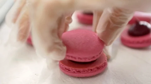 Making Pink Macaroons. Close up shot of connecting two halves of macaroons with Stock Footage 129917347