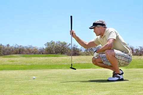 Making this putt worth it. Shot of a mature man lining up a putt on a green. Stock Photos