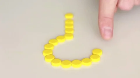 Making question mark using yellow pills 動画素材 79589997