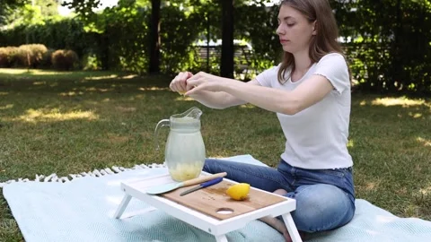 Making refreshing lemonade outdoors with fresh lemons in a sunny park Stock Footage 297370222