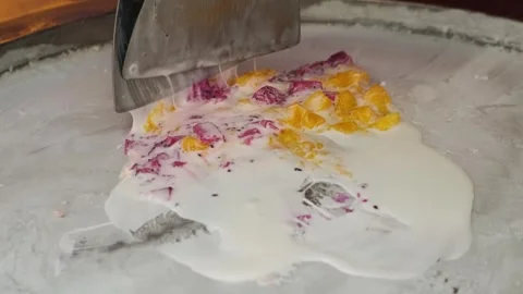 Making rolled ice cream with mixed dragon fruits and mango on a cold plate at a Video stock 284345486