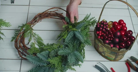 Making rustic christmas wreath. Hands holding green branches on rustic wooden Stock Footage 146226200