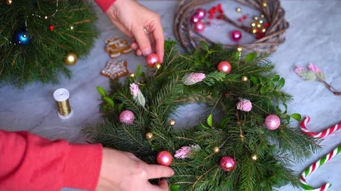Making rustic Christmas wreath. Hands decorate a wreath with pink round toys. Stock Footage 165995025