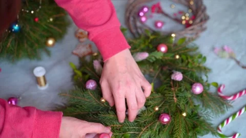 Making rustic Christmas wreath. Hands decorate a wreath with pink round toys. Stock Footage 165995028