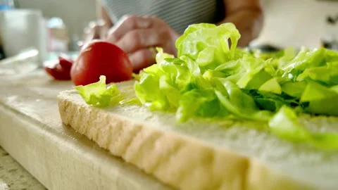 Making a salad sandwich. Lettuce on bread with tomato in background Stock Footage 339968177