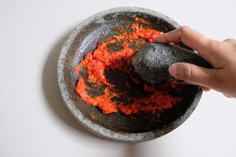 Making sambal using stone pestle and mortar. Stock Photos