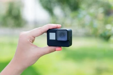 Making a selfie with action camera concept. Camera in woman hand. Close-up. Stock Photos