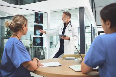 Making sense of the patients injury. a mature doctor analysing x-rays with his Stock Photos