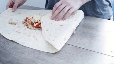 Making a shawarma or doner kebab with chicken meat and vegetables, wrapping i Stock Footage 106196744