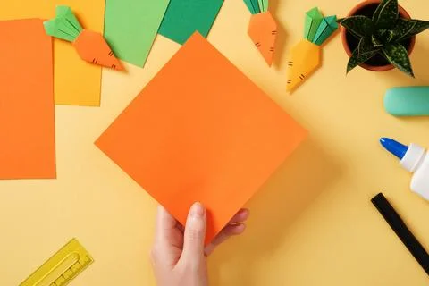 Making a simple origami carrot Easter craft. Take a square sheet of orange or Stock Photos