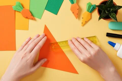 Making a simple origami carrot Easter craft. Fold the orange square sheet in  Stock Photos