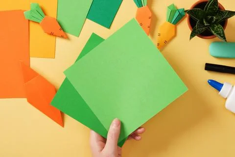 Making a simple origami carrot Easter craft. Take green colored paper to ma.. Stock Photos
