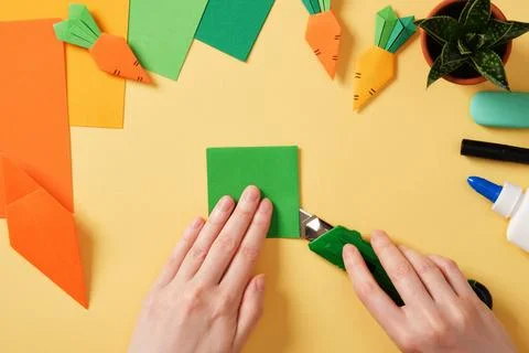 Making a simple origami carrot Easter craft. Cut a green sheet of paper wit.. Stock Photos