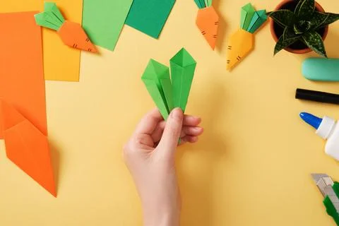 Making a simple origami carrot Easter craft. Make leaves from small pieces .. Stock Photos