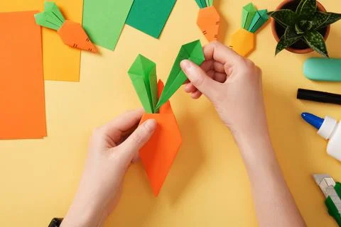 Making a simple origami carrot Easter craft. Insert the leaves into the ora.. Stock Photos