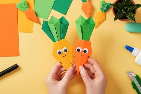 Making a simple origami Easter craft. Hands hold finished crafts of smiling.. Stock Photos