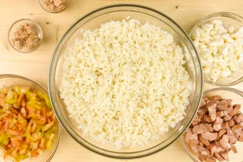 Making simple rice salad in a transparent bowl on wooden background - top vie Stock Photos