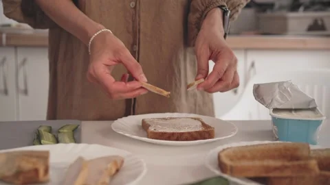 Making a simple sandwich in a kitchen with bread, spreads, and toppings Видео 338166782