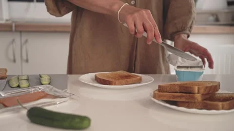 Making simple toast with cream cheese and cucumbers in a kitchen setting Stock Footage 338166797