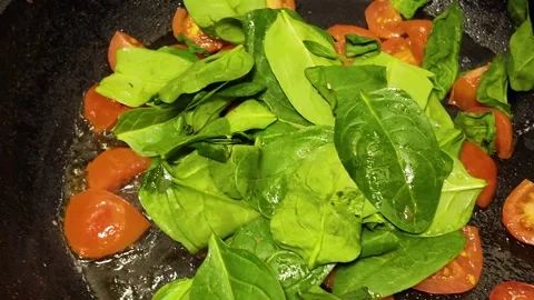 Making stewed tomatoes and fresh spinach in a frying pan for pasta Stock Footage 341616544
